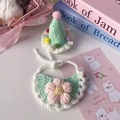 Close-up of handmade knit pet hat with pompoms and floral bib in pastel macaroon colors - One Size / Emerald Green Hat And Bib Style / Emerald Green Hat And Bib