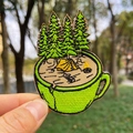 Detail einer Stickerei mit Campingzelt, Kaffeetasse und Kiefern für Kleidung - Camping Kaffeetasse Stil (PE5902CT)
