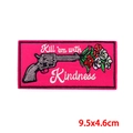 Nahaufnahme der Kill 'em with Kindness Pistolen-Stickerei mit bunten Blumen-Details - Güte Pistole Stil (PE9679CT)