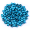 Gros plan de perles en bois d'érable bleu vif avec trous pour la création de bijoux DIY - Bleu