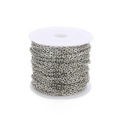 Close-up of shiny silver cross chain roll on white plastic spool for DIY jewelry making - White K/Silver