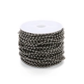 Macro shot of gunmetal iron ball chain neatly wound on white plastic spool for DIY jewelry - 1.5mm / Gun Black