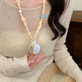 Detailed macro shot of a seashell pendant necklace featuring an orange printed ribbon - 2# Necklace-Orange-Shell