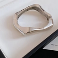 Gros plan d'un bracelet jonc en métal argenté torsadé irrégulier sur un plateau de présentation - Style Charnière Poli Brillant Argent (6#) / Argent