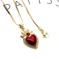 Détail macro du pendentif cœur doré avec pierre rouge et halo de cristaux sur chaîne box - Collier Cœur Couronne Baroque