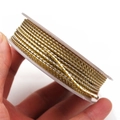 Macro detail of two-tone gold and silver metallic braided cord on white plastic spool - Gold and Silver Style