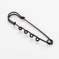 Detail macro view of a minimalist black metal multi-loop safety pin for DIY crafts - Black