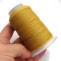 Primo piano di filo cerato dorato su rocchetto per intrecci fai-da-te e artigianato - 6 fili / Giallo Oro (A43)