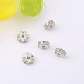 Close-up of 5 silver flower-shaped spacer beads with micro-set crystals for jewelry making - 4mm / Silver