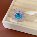 Primo piano di un elegante anello a girasole con pietra centrale in zircone blu vivace - Anello a Fiore