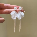Close-up detail of white pearl earrings with fabric petals and long silver tassels - Silver Earring Post-White