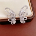 Close-up of butterfly ear clips encrusted with brilliant white cubic zirconia stones. - Hollow Silver Pair