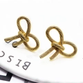Elegant gold bow earrings with a textured rope knot design in a bright studio setting - Rope Knot Bow (8)