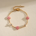 Detalle de una pulsera de acero inoxidable dorada con flores rosas y circonitas - Flor Rosa / Rosa