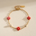 Detalle de pulsera de acero dorado con flores de trébol rojas y circonitas claras - Flor Roja / Rojo