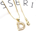Macro shot of gold letter D pendant with cubic zirconia inlay on a box chain necklace - Letter D