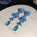 Detail shot of light luxury blue zircon rose drop earrings on cream display - Rose Flower Tassel Earrings