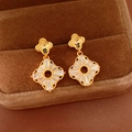 Macro view of engraved golden clover studs with sparkling zircon-set dangle frame - Gold