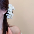 Vue détaillée du clip latéral en forme de fleur de lys blanc porté par un mannequin. - Pince à Cheveux (11#) / 1 Pièce / Blanc