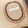 Detail view of a beaded lace necklace with lavender, black, and bronze glass beads. - Purple