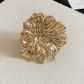 Close-up of golden oversized metal flower ring with hammered texture and organic petal design. - Ring (Size 7) / Gold