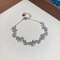 Detalle de una pulsera con dijes de mariposas de circón brillante y cierre de langosta - Lazo / Plateado-Blanco