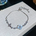 Detailansicht eines silbernen Armbands mit Zirkon, Katzenaugenstein und blauer Blüte. - Blume Schmetterling Stil / Silber