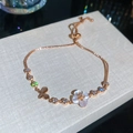 Elegantes rotgoldenes Armband mit weißer Blume, Schmetterlingsanhänger und Zirkonsteinen. - Blume Schmetterling Stil / Roségold