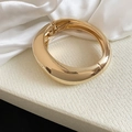 Close-up of a chunky geometric gold metallic bangle with a high-shine finish for women - Style 1 / Gold