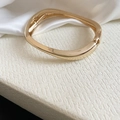 Close-up of a gold irregular geometric metal bangle with a glossy high-end finish - Style 5 / Gold