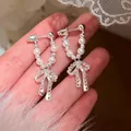 Primo piano di orecchini a fiocco argentati con eleganti perle finte in mano. - Argento