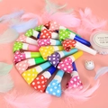 Sifflets de fête à pois multicolores disposés sur un fond rose avec des plumes douces - Style à Pois