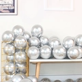 Glossy silver metallic latex balloons displayed in a gold iron basket for party decor - Silver