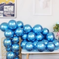 Stack of metallic blue latex balloons in a gold wire basket on a white table - Blue