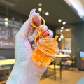 Dettaglio di un portachiavi arancione con sabbie mobili liquide, ghiaccio e campanellino - Arancione