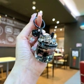 Handheld detail of a mini black pearl milk tea keychain with bell and ice cube charms - Black