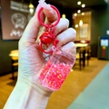 Detail of pink liquid glitter keychain with star sequins and red bell accent - Lobster Clasp Style / Red
