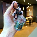 Close-up of liquid keychain with colorful star sequins and a black metal bell charm - Lobster Clasp Style / Black