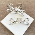 Detailed view of silver metallic pleated bow cuff bracelet and matching ring set on white box - Mirror Bow Jewelry Set (70#) / Silver