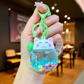 Macro detail of Maneki Neko liquid keychain with blue glitter, colorful sequins and green bell - Colored Hardware Luminous Style / Green