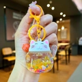 Close-up of Maneki Neko liquid keychain with gold glitter and red bell accessory - Orange