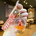 Detail van vloeibaar zand Capybara-sleutelhanger met aardbeienhoed en glitters - Gradiënt Band / Aardbei Capibara Wekker