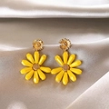 Detail view of stylish yellow daisy drop earrings resting on soft champagne satin fabric - Yellow Daisy Flower (HE32319-1) / Gold And Yellow