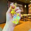 Gros plan d'un porte-clés à sable liquide avec perles jaunes, cloche et papillon pailleté - Réservoir de gaz flocon de neige / Jaune Avec Boucle