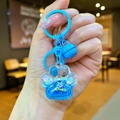 Primer plano de un llavero de pata de gato azul con arena líquida movible en la mano - Estilo Mini / Cierre de Langosta / Azul
