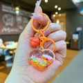 Detail van hartvormige sleutelhanger met oranje vloeistof en bijpassende bel - Mini Glinsterend Hart / Mini Stijl / Kreeft Sluiting / Oranje
