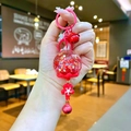 Dettaglio del ciondolo a fiore di ciliegio rosso con sfera glitter e campanella - Stile Chiusura a Moschettone / Rosso