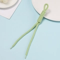 Detail of light green hand-woven rope with intricate knotting and clear plastic aglet - Green