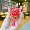 Dettaglio del portachiavi artigianale con paillettes a stella e ciondolo a fiore di ciliegio - Senza Portachiavi / Scacciapensieri Luminoso Rosso