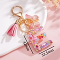 Dettaglio portachiavi lettera E in resina con paillettes a cuore rosa e nappina - Rosa E